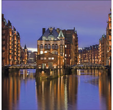 Le Speicherstadt de Hambourg avec des entrepôts illuminés et des ponts sur l''eau la nuit.