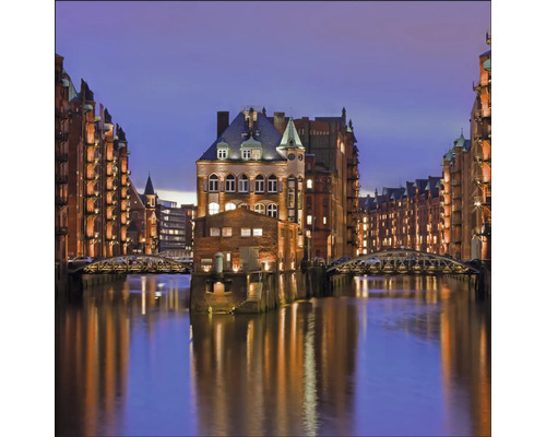 Le Speicherstadt de Hambourg avec des entrepôts illuminés et des ponts sur l''eau la nuit.