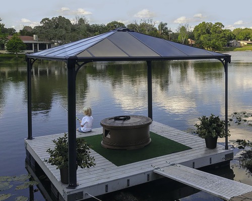 Pavillon auf einem Ponton mit Feuerstelle, Dekoration und Kind beim Angeln am See