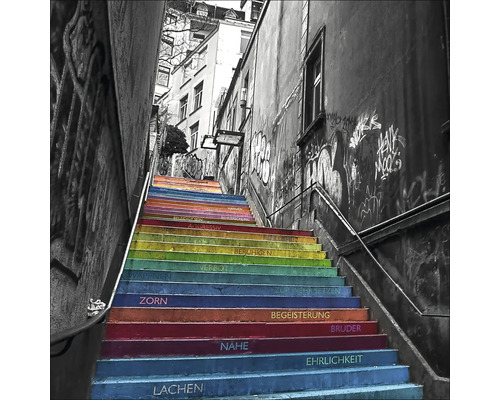 Treppe mit Regenbogenfarben und aufgemalten Wörtern zwischen Gebäuden