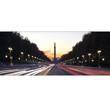 La Colonne de la Victoire à Berlin, flanquée de lampadaires et d''arbres le long d''une rue animée au crépuscule.