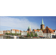 Panorama de Lübeck avec la Trave, les bâtiments historiques et les clochers sous un ciel bleu.