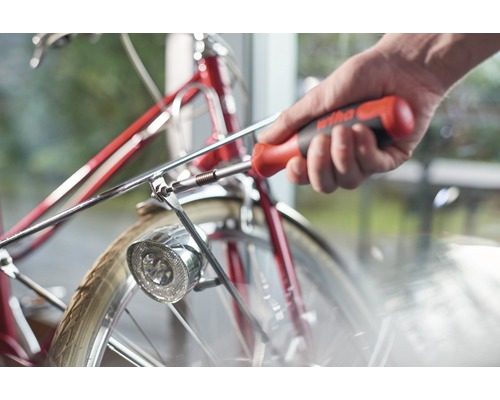 Une personne fixe la lampe à un vélo avec un tournevis.