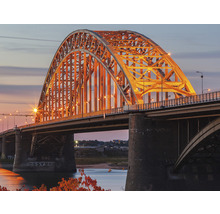 Vue sur un pont en arc illuminé au crépuscule.