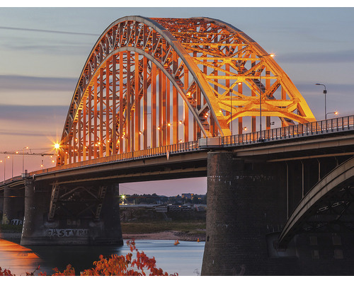 Vue sur un pont en arc illuminé au crépuscule.