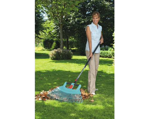 Une femme ratisse les feuilles avec un râteau à feuilles dans le jardin.
