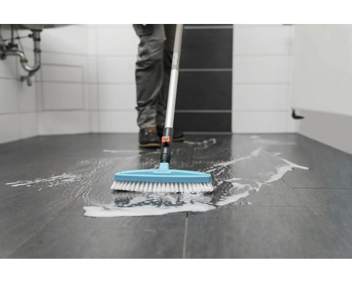 Personne nettoie le sol de la salle de bain avec une brosse de nettoyage