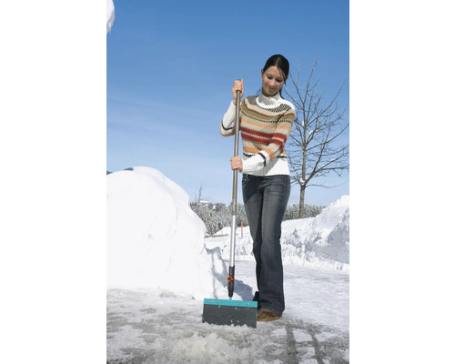 Une femme déblaie la neige avec un chasse-neige.