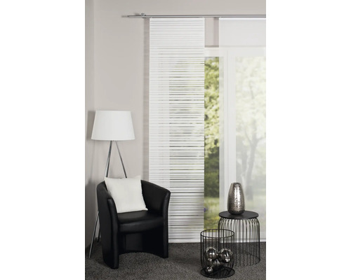 Salon avec rideaux coulissants, fauteuil, lampadaire et objets de décoration pour une ambiance chaleureuse.