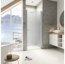 Salle de bains lumineuse avec douche, lavabo et baignoire devant une fenêtre avec vue sur le lac