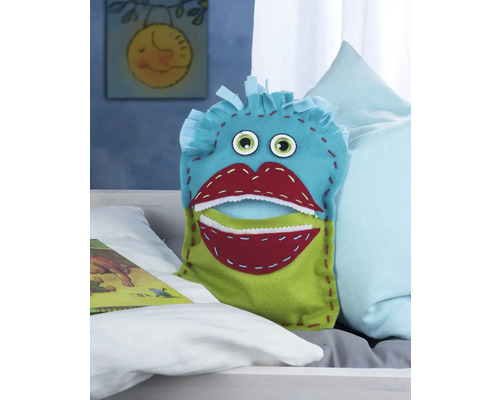 Coussin décoratif avec visage de monstre sur un lit