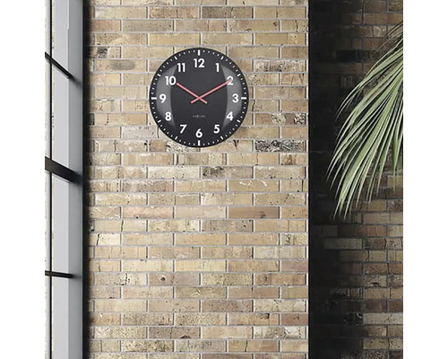 Horloge murale noire avec aiguille rouge devant un mur de briques