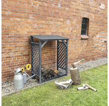Holzlagerregal aus Metall mit Brennholz, Axt und Giesskanne im Garten vor einer Ziegelmauer