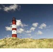 Phare rayé rouge et blanc sur une dune sous un ciel bleu