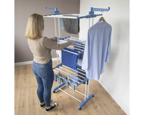 Frau hängt Wäsche auf einem Wäscheständer im Innenbereich.