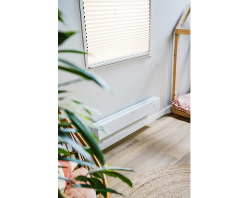 Scène avec un radiateur convecteur mural blanc dans une pièce avec un lit cabane en bois
