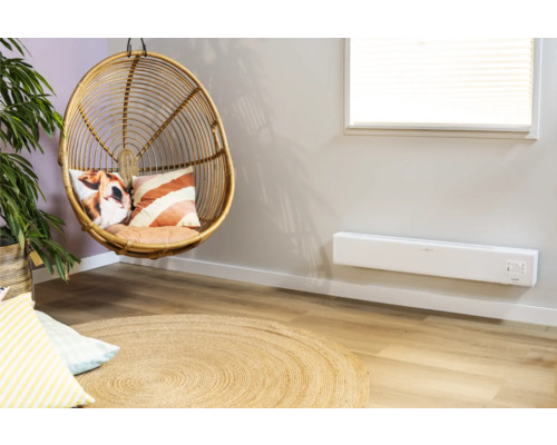 Salon avec fauteuil en rotin, coussins, tapis et radiateur