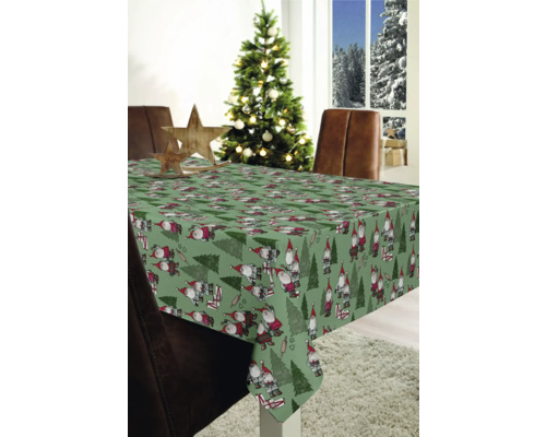 Table avec une nappe de Noël avec des nains et des sapins dans une pièce décorée.
