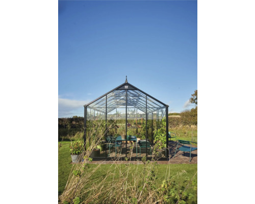 Serre avec des murs en verre et un cadre noir dans le jardin.