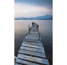 Ein Holzsteg führt ins ruhige Wasser mit Bergen im Hintergrund.