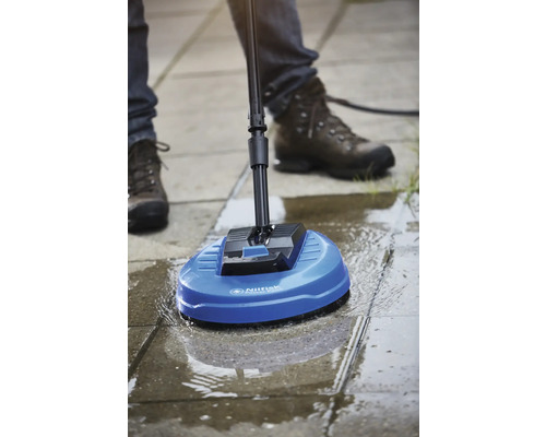 Une personne utilise un nettoyeur de surface Nilfisk pour nettoyer une surface pavée.