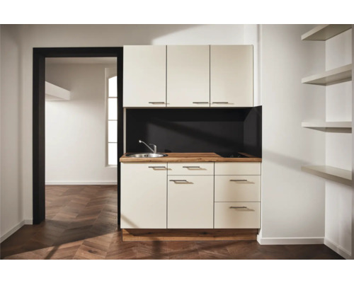 Cuisine compacte avec évier, plaque de cuisson et espace de rangement dans une pièce lumineuse et moderne.