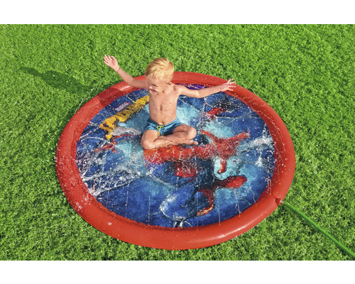 Junge sitzt in einem runden Wassersprinkler auf Rasen