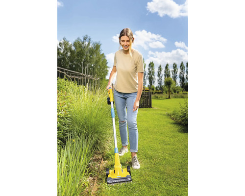 Frau benutzt einen Fugenkratzer im Garten.