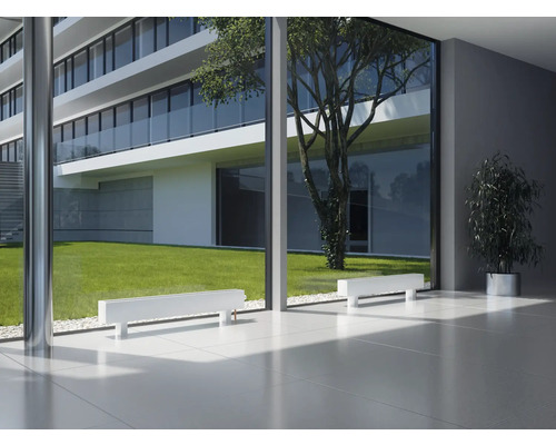 Intérieur avec radiateurs blancs devant une baie vitrée donnant sur un bâtiment moderne et un espace vert