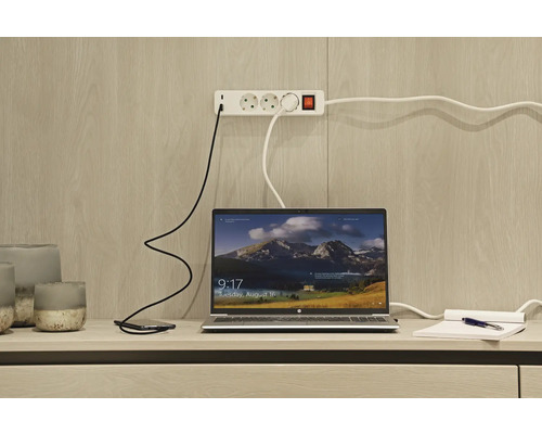 Ordinateur portable, smartphone et multiprise sur un bureau.