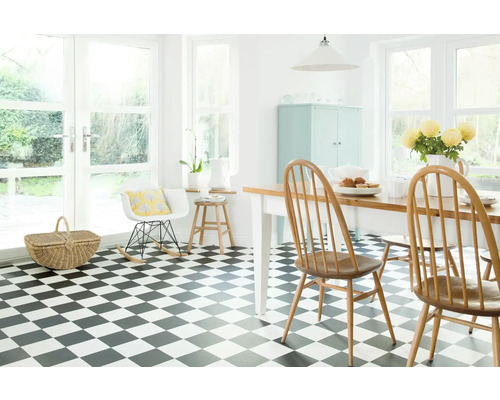 Pièce lumineuse avec sol à damier, table à manger et chaises.