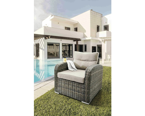 Fauteuil tressé avec coussins à côté de la piscine et de la maison