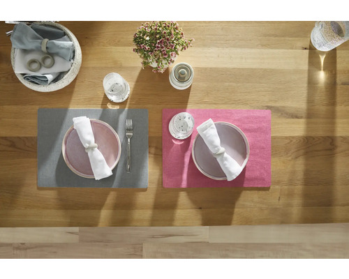 Tischdekoration mit Platzsets, Tellern, Servietten und Besteck auf Holztisch
