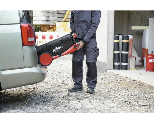 Ein Handwerker hievt einen Werkzeugkoffer von Wiha in einen Kofferraum.