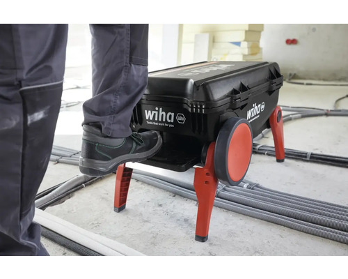 Wiha Werkzeugkoffer mit Trittfunktion und Bein steht auf einer Baustelle mit dem Fuß einer Person darauf