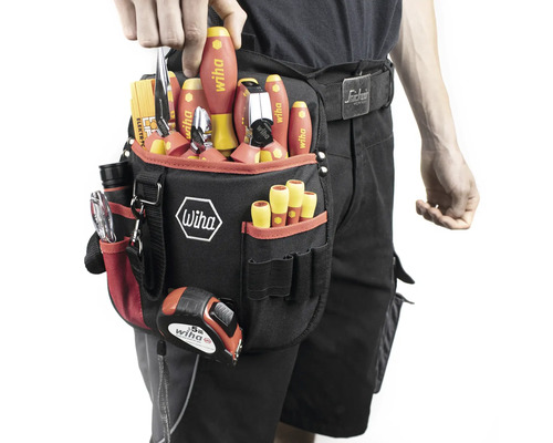 Person mit Werkzeuggürtel, gefüllt mit Schraubendrehern, Zangen und einem Maßband