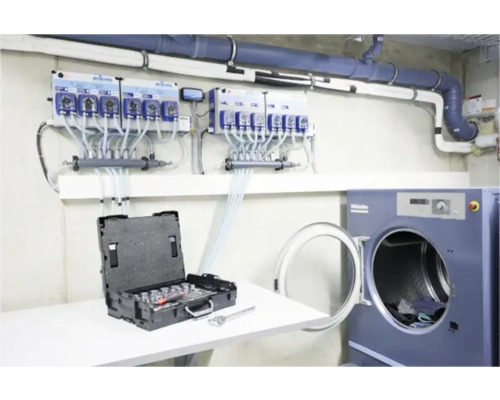 Dosieranlage neben Waschmaschine und Werkzeugkasten
