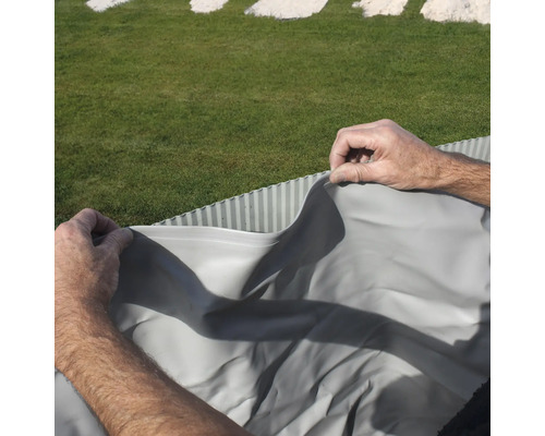 Person verlegt Teichfolie im Garten.