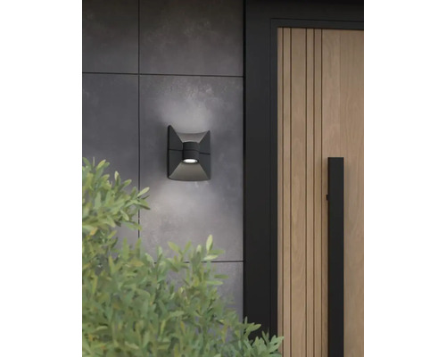 Quadratische Wandleuchte an einer Hauswand neben einer Holztür.