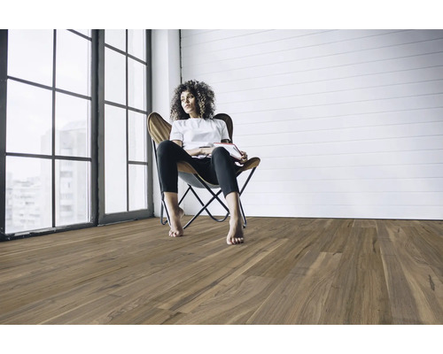 Wohnzimmer mit Holzboden und einer Frau, die auf einem Sessel sitzt.