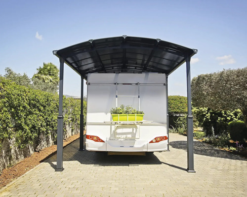 Carport mit Wohnwagen auf einem gepflasterten Hof.