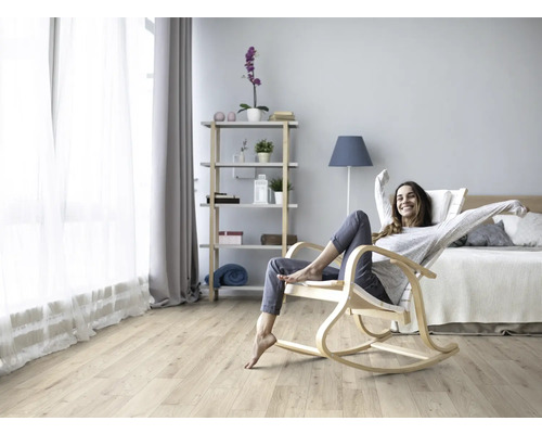 Wohnzimmer mit hellem Laminatboden und einer Frau, die in einem Schaukelstuhl sitzt.