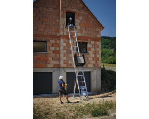 Bauaufzug vor einem zweistöckigen Haus im Rohbau mit zwei Bauarbeitern
