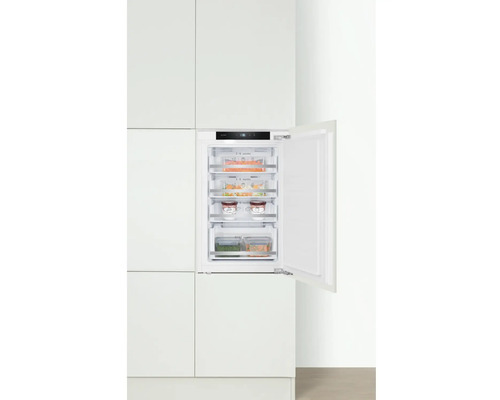 Congélateur intégré avec porte ouverte dans une cuisine blanche