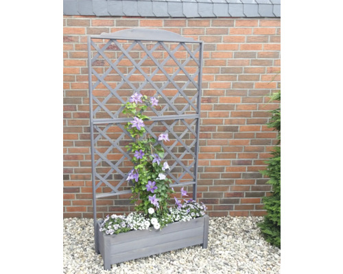 Jardinière en bois avec treillis et plantes devant un mur de briques