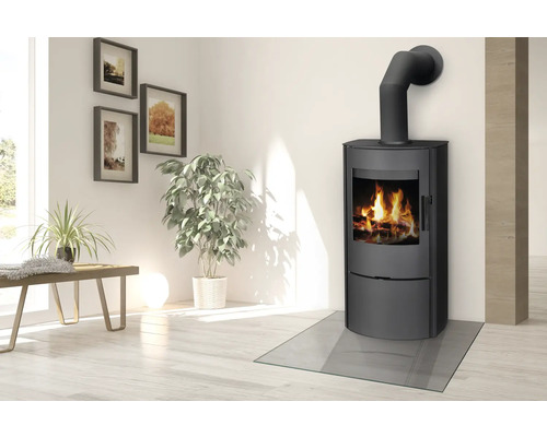 Poêle à bois avec plaque de sol en verre dans un salon lumineux.