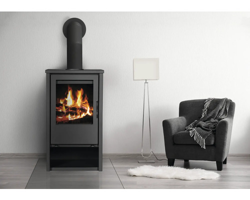 Poêle à bois avec bois de chauffage à côté d''un fauteuil et d''un lampadaire