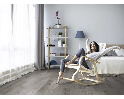 Heller Wohnraum mit Holzboden, Schaukelstuhl und einer entspannten Frau