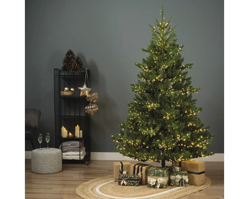 Sapin de Noël décoré avec des cadeaux sur un tapis dans une pièce
