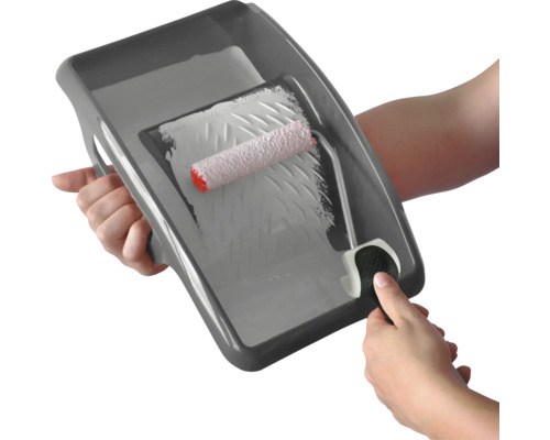 Une personne tient un bac à peinture avec un rouleau à peinture dans la main